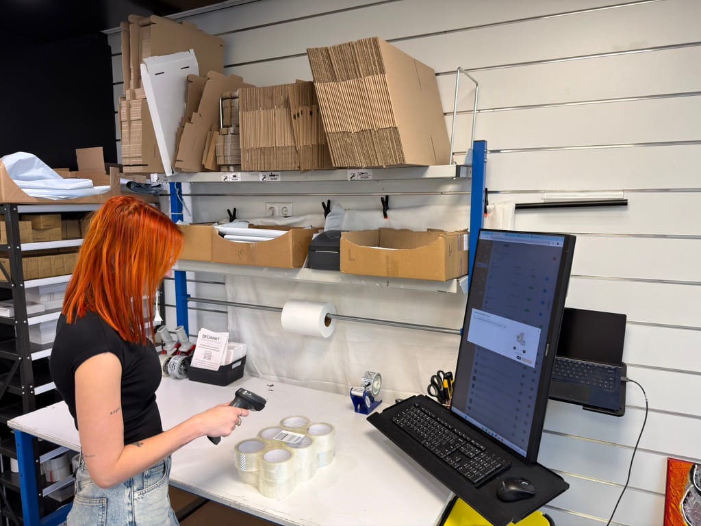 Someone packing an order and scanning a product at the packing station, with ShopLinkr on screen.