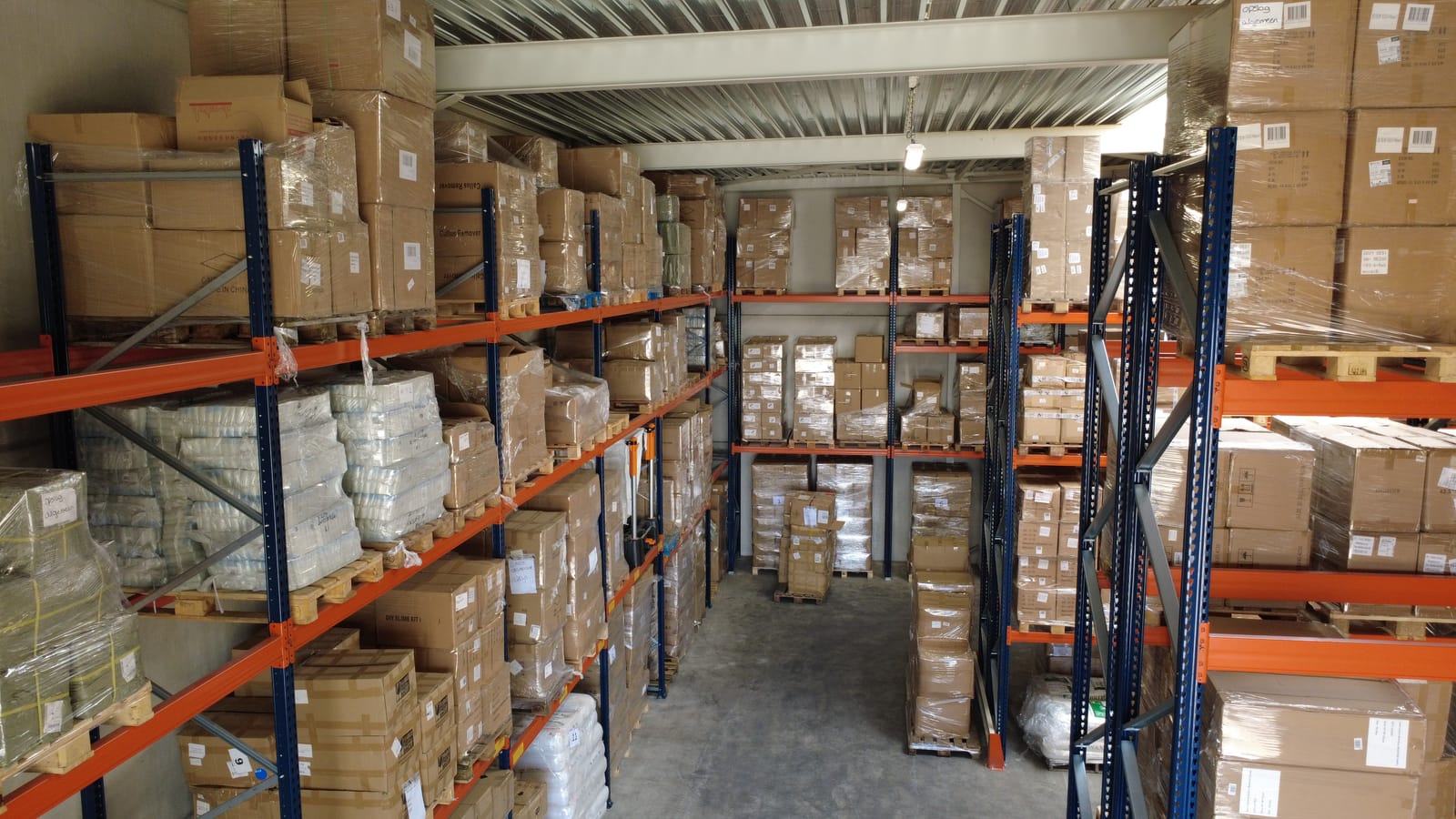 Warehouse with pallet racking full of packed products and boxes.